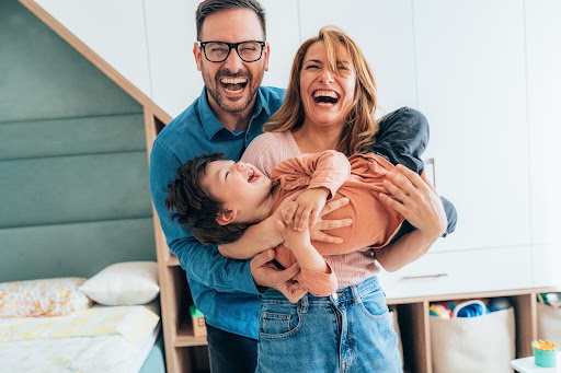 Un homme, une femme et un enfant jouent en rigolant.